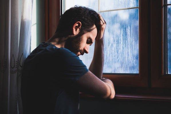 depressed man near window
